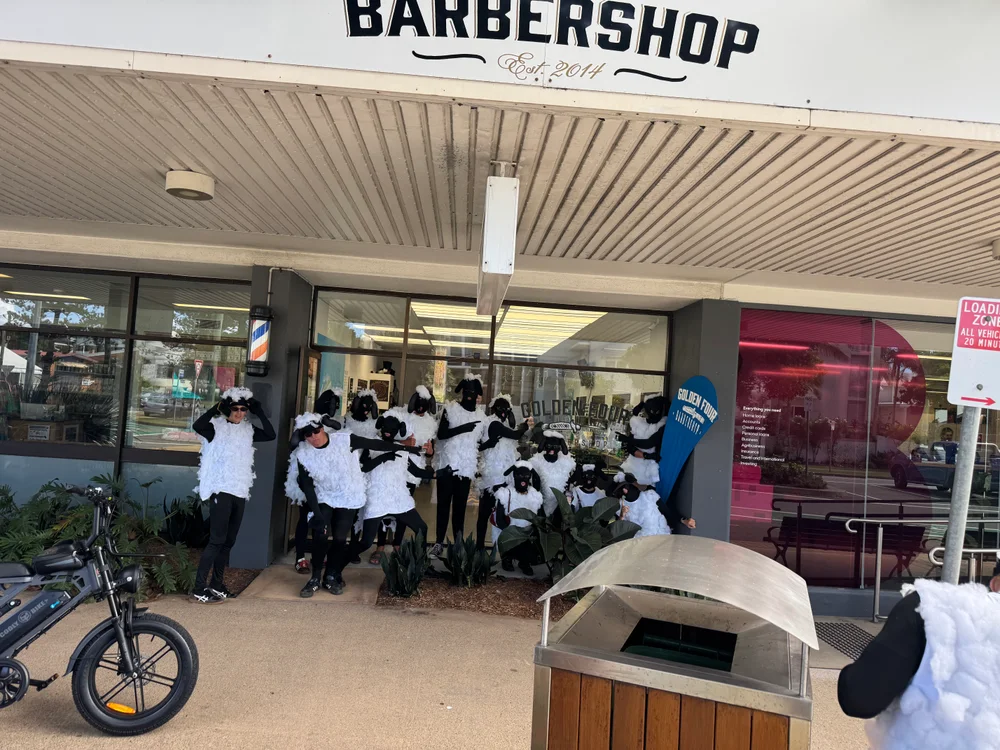 A group in sheep costumes having a laugh outside Golden Four Barbershop