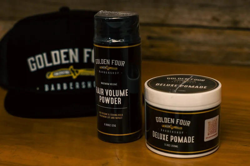 Golden Four hair volume powder and deluxe pomade alongside a branded cap